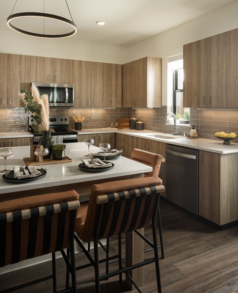 A modern kitchen with wooden cabinets and a bar area.