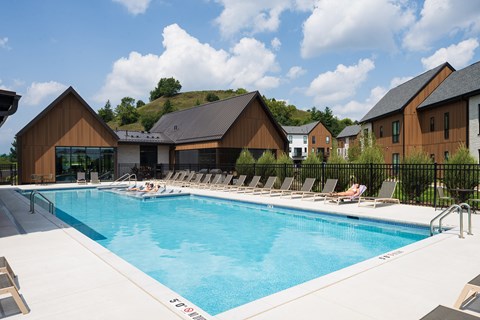 A large swimming pool with lounge chairs and a building in the background.