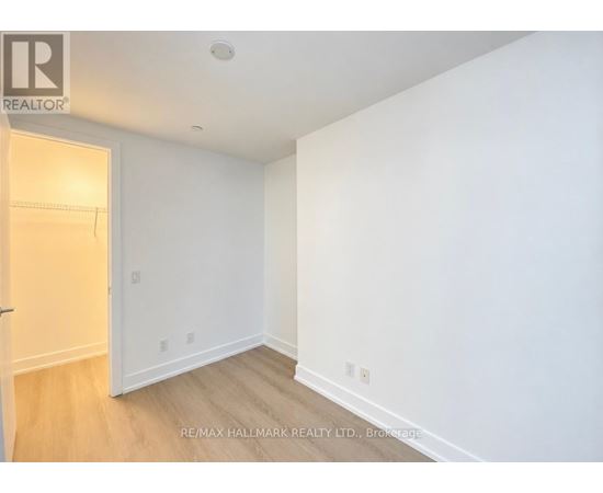 A white room with a wooden floor and a door on the left.
