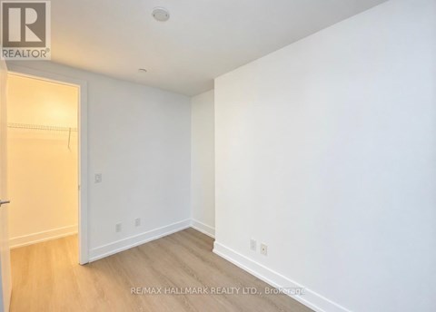 A white room with a wooden floor and a door on the left.