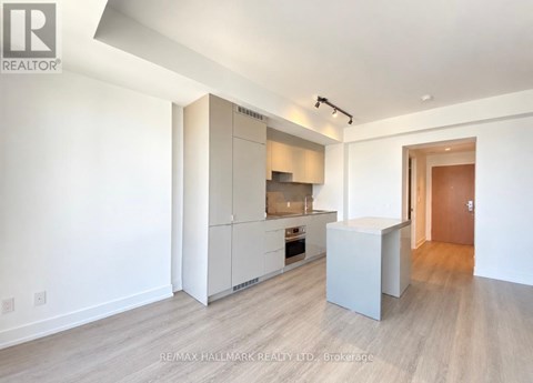A spacious kitchen with white cabinets and a wooden floor.
