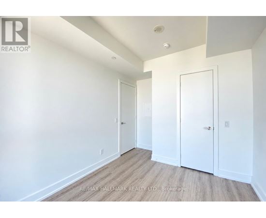 A brokerage image of a white room with wood flooring and two doors.