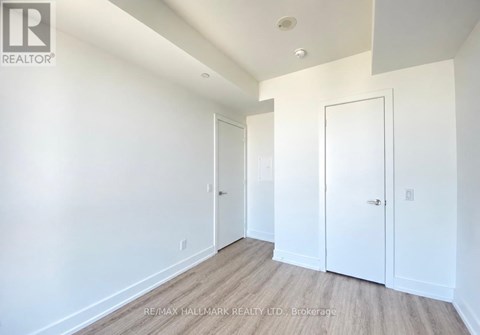 A brokerage image of a white room with wood flooring and two doors.
