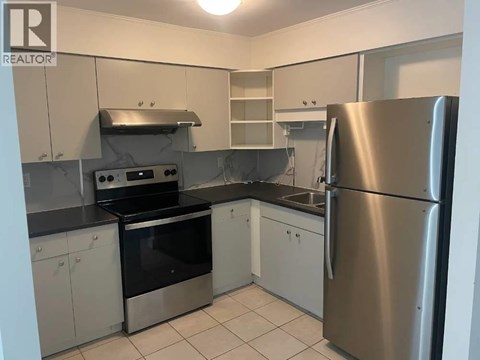 A kitchen with a stainless steel refrigerator, oven, and sink.