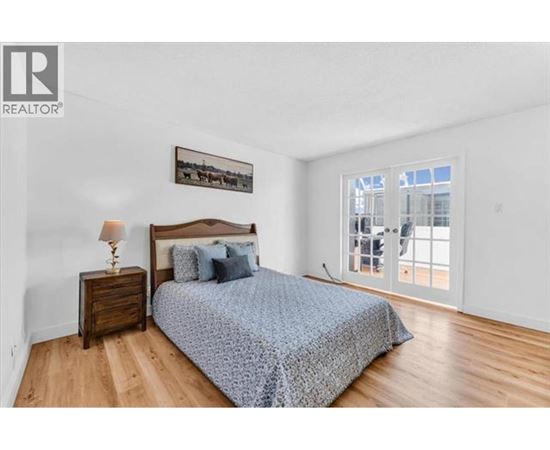 A bedroom with a bed, nightstand, and a picture on the wall.