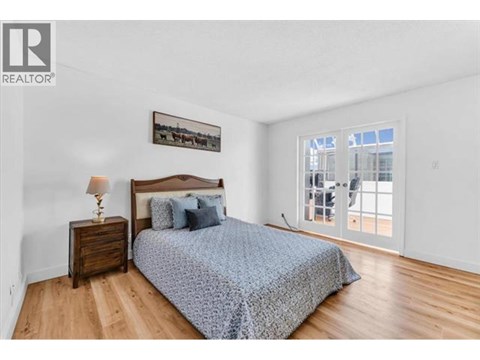 A bedroom with a bed, nightstand, and a picture on the wall.