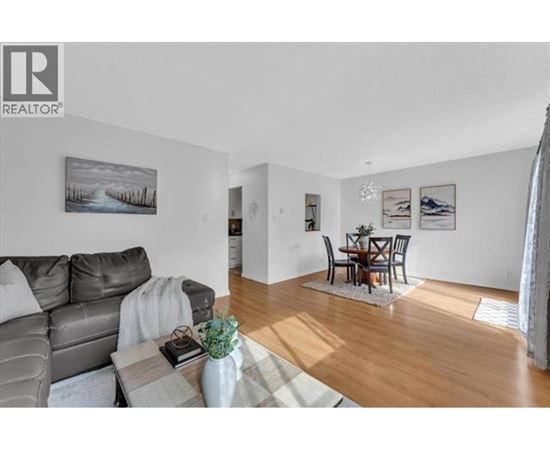 A living room with a grey couch and a coffee table with a vase of flowers on it.