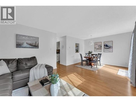 A living room with a grey couch and a coffee table with a vase of flowers on it.