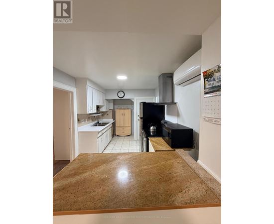A kitchen with a wooden counter top and white cabinets.
