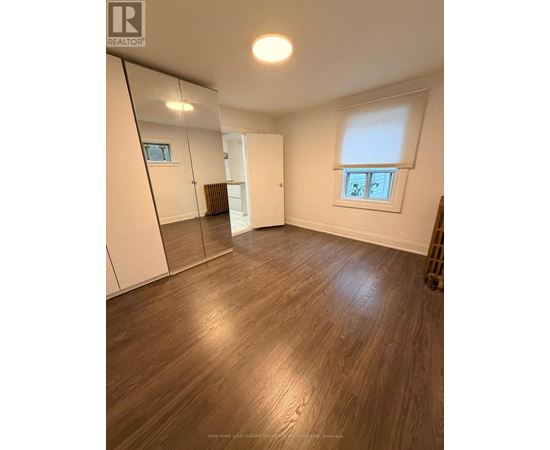 A room with wooden flooring and a large mirror on the wall.