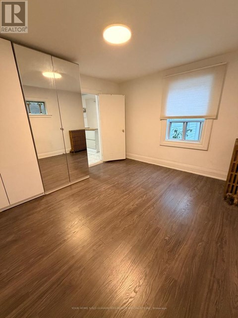 A room with wooden flooring and a large mirror on the wall.