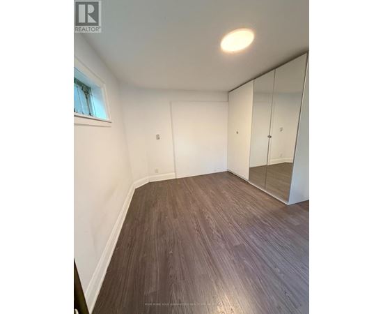 A room with wooden flooring and a large mirror.