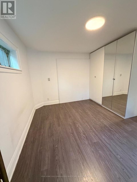 A room with wooden flooring and a large mirror.