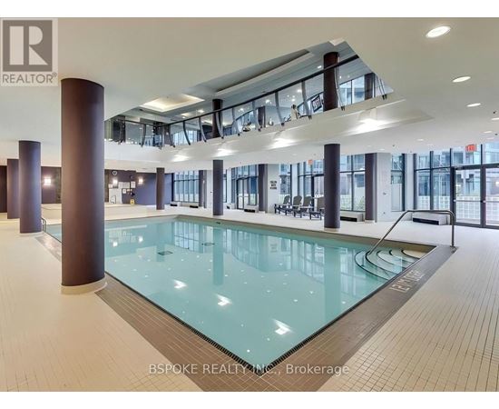 A large indoor swimming pool with a glass bottom and a tiled floor.