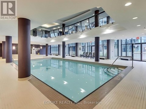A large indoor swimming pool with a glass bottom and a tiled floor.