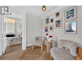 A bedroom with a bed, two chairs, and pictures on the wall.