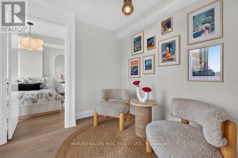 A bedroom with a bed, two chairs, and pictures on the wall.
