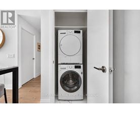A white washer and dryer are stacked on top of each other in a small space.