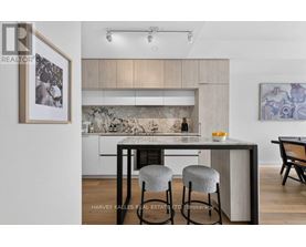A modern kitchen with a bar stool and a framed picture on the wall.