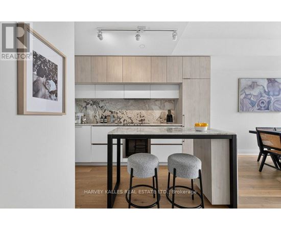 A modern kitchen with a bar stool and a framed picture on the wall.