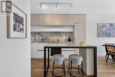 A modern kitchen with a bar stool and a framed picture on the wall.