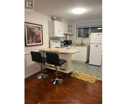 A kitchen with a white fridge, black chairs and a wooden table.