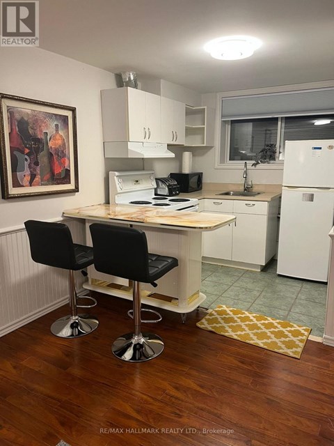 A kitchen with a white fridge, black chairs and a wooden table.