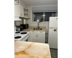 A kitchen with white appliances and cabinets.