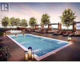 A pool with people swimming in it and lounge chairs around it.