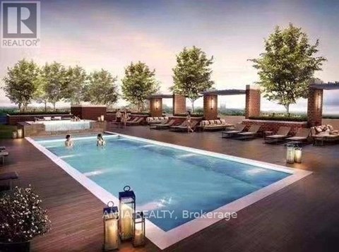 A pool with people swimming in it and lounge chairs around it.