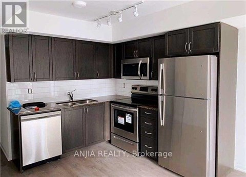 A kitchen with dark brown cabinets and stainless steel appliances.