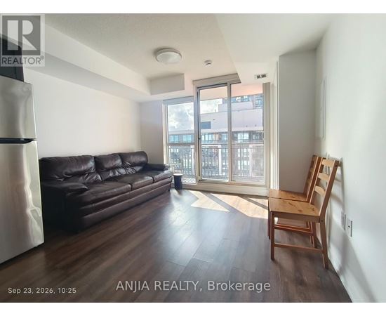 A living room with a black leather couch and wooden floors.