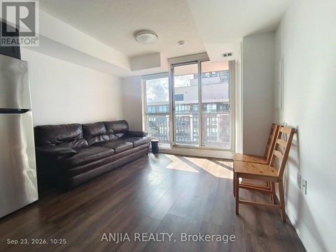 A living room with a black leather couch and wooden floors.
