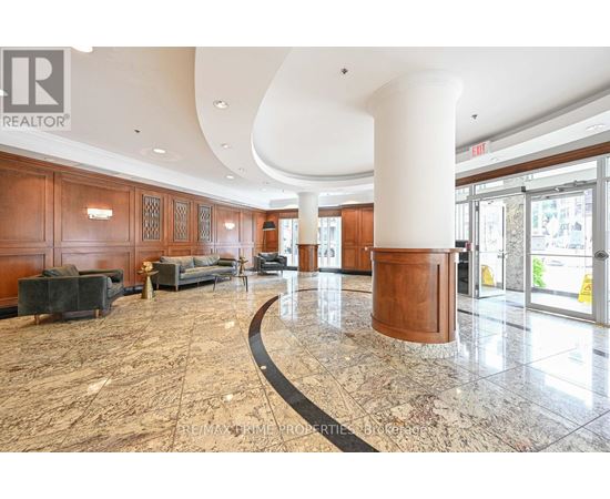 A large, open lobby with a marble floor and wooden furnishings.