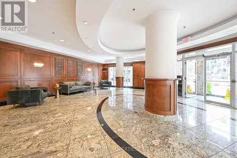 A large, open lobby with a marble floor and wooden furnishings.