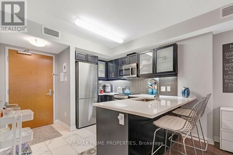 A kitchen with a sink, refrigerator, and a dining table.