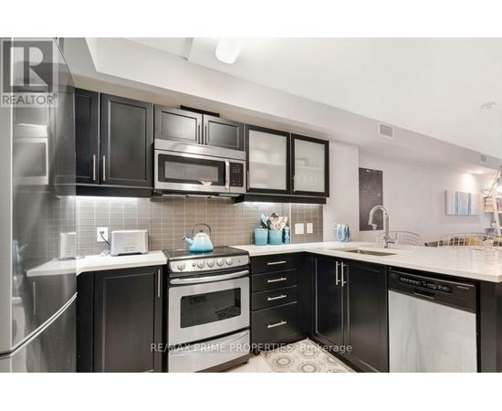 A modern kitchen with black cabinets and stainless steel appliances.