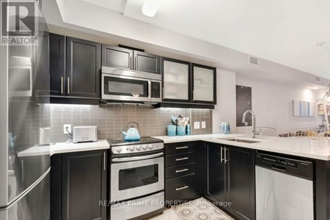 A modern kitchen with black cabinets and stainless steel appliances.