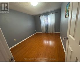 A room with wooden flooring and a door on the right side.