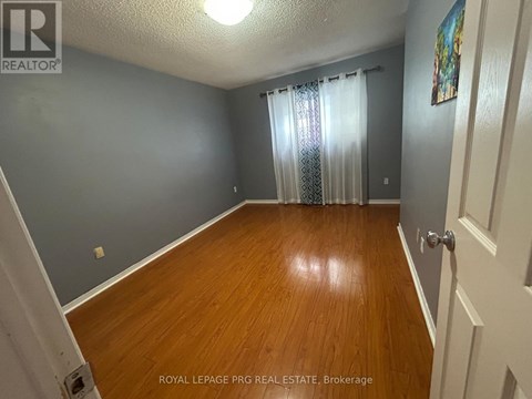 A room with wooden flooring and a door on the right side.
