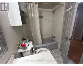 A bathroom with a white toilet, a bathtub, and a shower curtain.