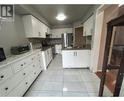 A kitchen with white cabinets and a marble floor.