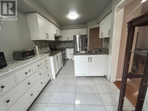 A kitchen with white cabinets and a marble floor.