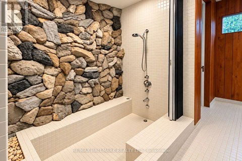 A bathroom with a stone wall and a walk-in shower.