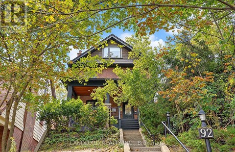 A house numbered 92 is surrounded by trees.