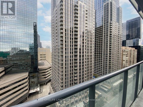 A glass building with the letters "R" on it is in the foreground of a cityscape.
