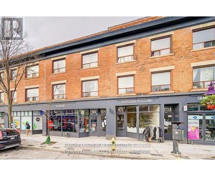 A street view of a building with shops on the ground floor and a sign for a genetics clinic on the top floor.