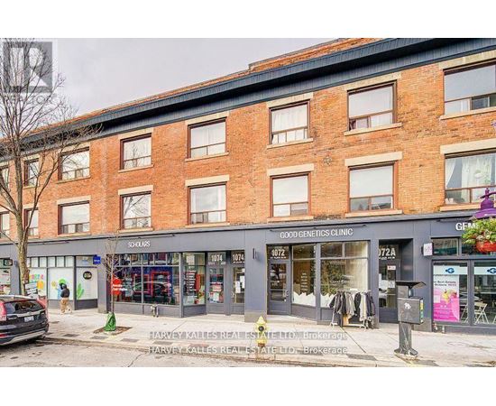 A street view of a building with shops on the ground floor and a sign for a genetics clinic on the top floor.