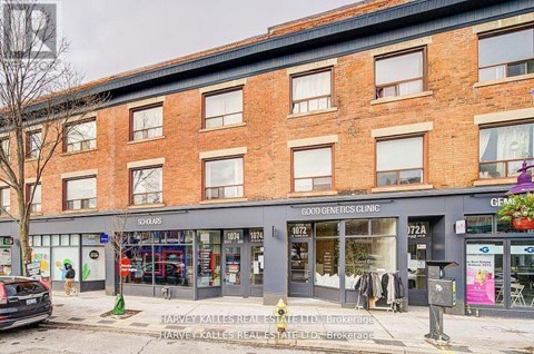 A street view of a building with shops on the ground floor and a sign for a genetics clinic on the top floor.