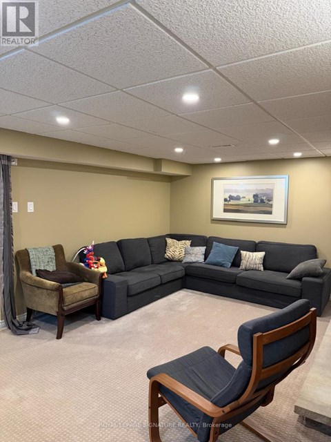 A living room with a grey couch, a brown chair and a painting on the wall.